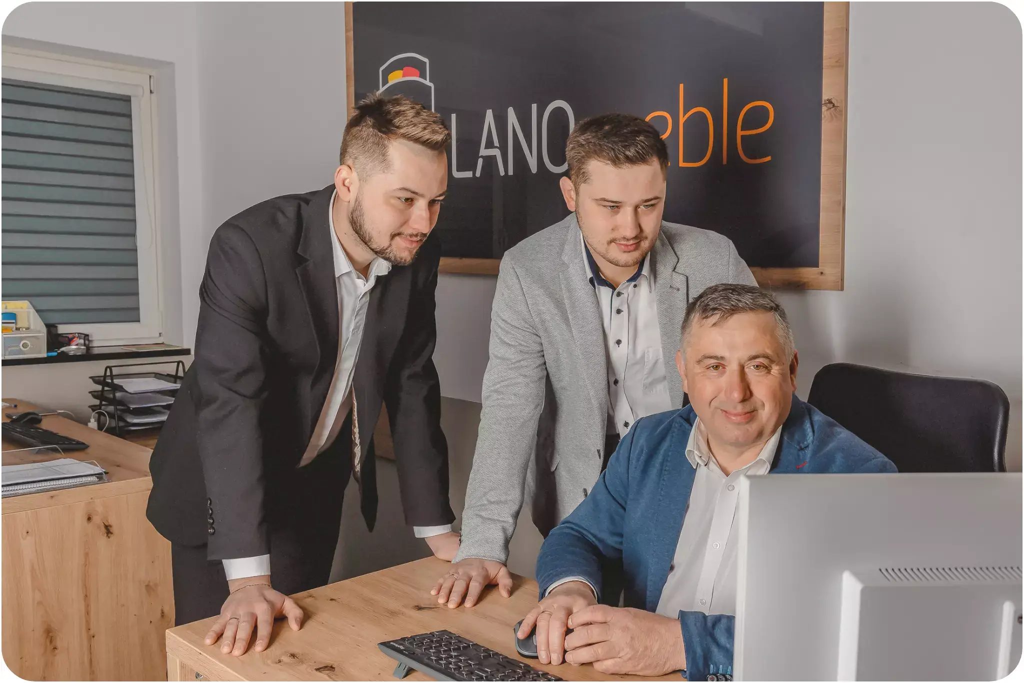 Fotka zakladatelů značky LANO. Otec sedí u stolu, dva synové stojí za ním